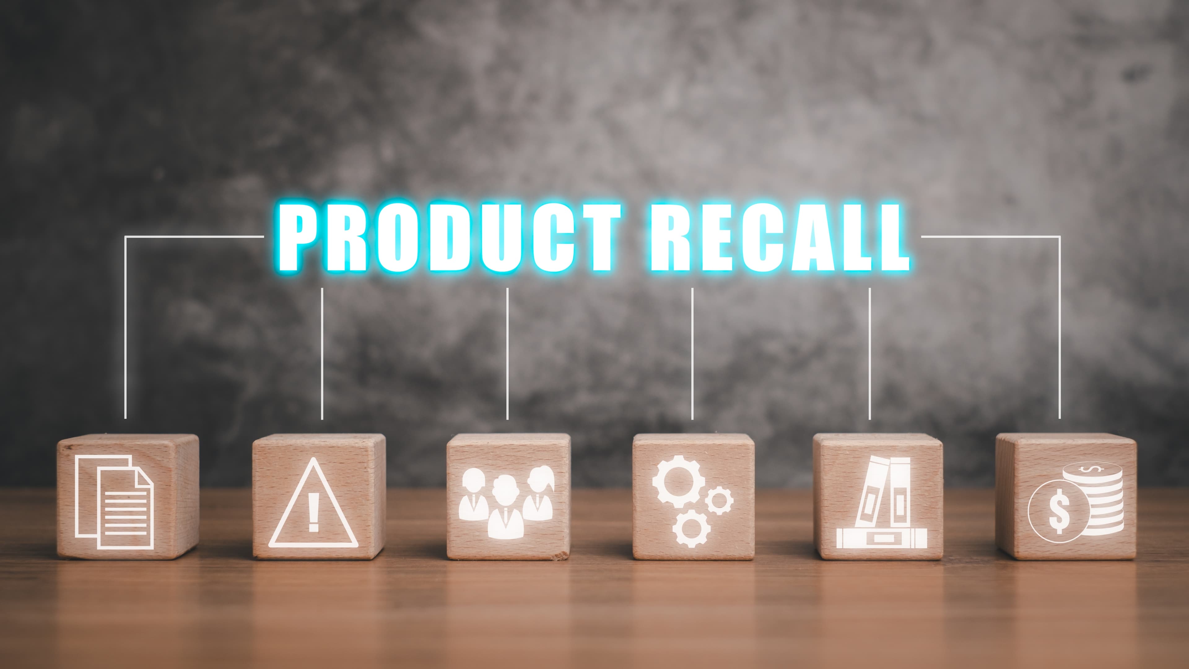Bauklötze mit Symbolen. Darüber Schriftzug Product Recall.