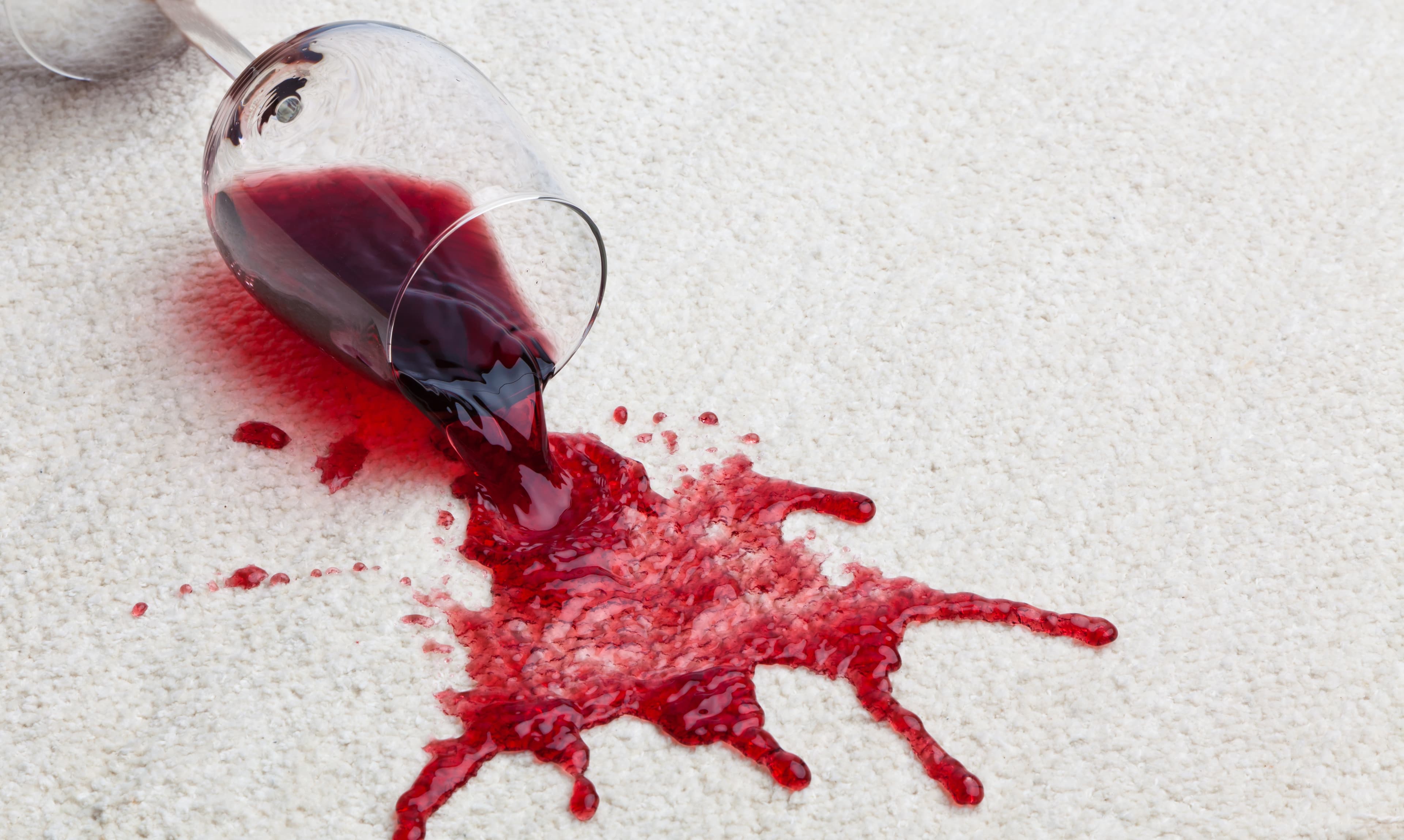 Weinglas auf Teppich. Wein läuft auf Teppich.